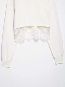 Detail of white sweatshirt featuring elegant lace patchwork hem for a layered look
