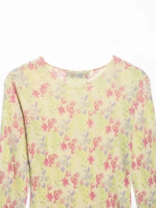 Détail d'un haut en tricot à fleurs roses et violettes sur tissu jaune clair