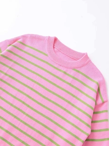 Gros plan sur le col rond et la texture rayée rose et verte de ce pull en maille douce