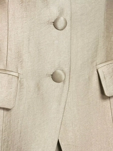 Close-up of champagne satin blazer featuring fabric-covered buttons and flap pockets