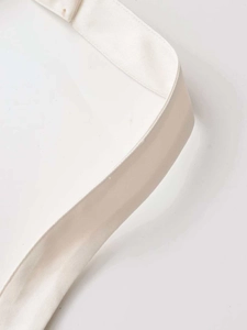 Macro detail of the creamy white halter dress showing thick twill fabric and fine stitching