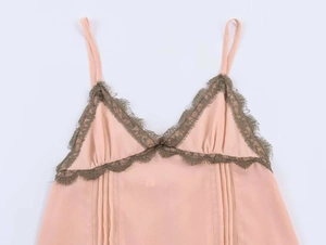Detail of pink camisole dress showing V-neckline with green eyelash lace and pleated fabric
