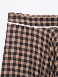 Detailed view of brown gingham fabric with delicate white lace trim and neat stitching