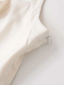 Detailed view of off-white dress side seam featuring a seamless invisible zipper and fine stitching