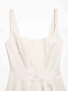 Detail of light beige corset-style dress with square neckline and structured seams