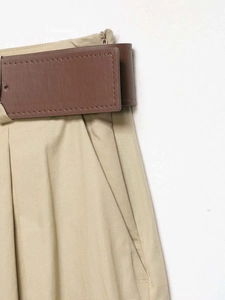Détail du pantalon kaki à taille haute avec plis et ceinture en similicuir marron élégante