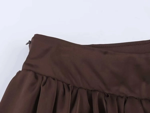 Détail de la jupe satinée marron foncé à taille haute avec plis et fermeture éclair invisible