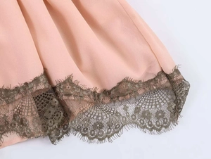 Detail of pink summer dress featuring dark green eyelash lace trim and scalloped edges