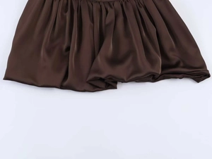 Détail du tissu en satin marron café avec une structure plissée et ourlet bulle