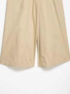 Détail du pantalon large beige montrant la texture du tissu naturel et les coutures de l'ourlet