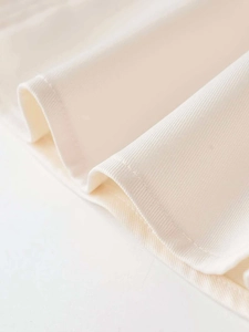 Detail of off-white halter dress showing high-quality twill fabric and neat edge stitching