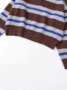 Macro shot of V-neck striped knit sweater showing ribbed cuffs and textured mixed fabric