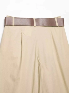 Détail d'un pantalon large kaki avec ceinture en cuir marron foncé et texture en coton