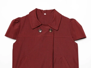 Détail d'une chemise à carreaux rouge foncé avec col à revers et deux boutons bruns
