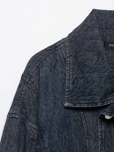 Detail of vintage acid wash texture on dark blue denim jacket with sharp collar stitch