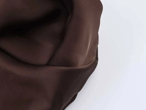 Vue détaillée du tissu en satin marron foncé montrant la texture lisse et les plis