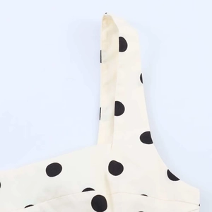 Detailaufnahme des schmalen Trägers und schwarzes Polka-Dot-Muster auf beigem Stoff