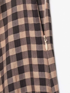 Detailed close-up of invisible zipper closure on brown gingham checkered skirt fabric