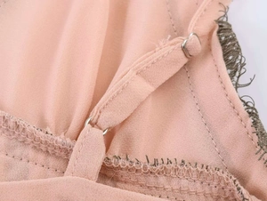 Detail of adjustable thin shoulder straps with metal buckle and delicate dark lace trim