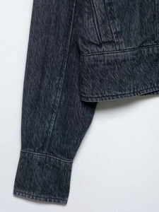 Detail of vintage grey denim jacket showing unique wavy washed texture and cuff seams