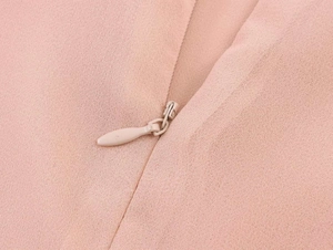 Detail view of the hidden zipper on a light pink lace patchwork summer mini dress