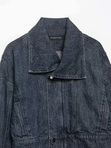 Close-up of dark blue denim jacket showing wave texture wash and metal button details