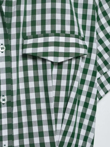 Detail of green gingham shirt dress featuring white buttons and a front flap pocket