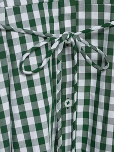 Close-up of green and white gingham dress with waist tie bow and button details
