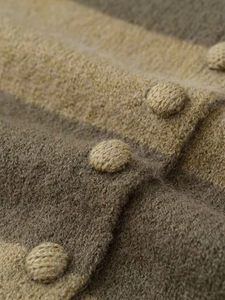 Detail view of woven buttons and striped knit texture on a long sleeve sweater