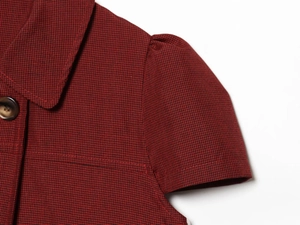 Détail de chemise à carreaux rouge et noir avec col à revers et manches bouffantes