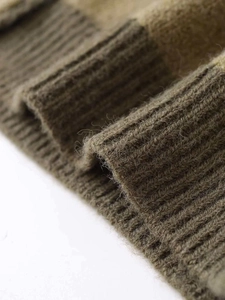 Close-up of olive green and beige knit sweater with fuzzy wool texture and ribbed cuffs