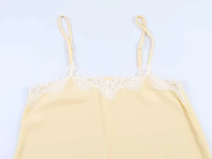 Close-up of delicate white lace trim on the neckline of a pale yellow camisole top