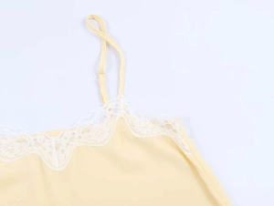 Detail of light yellow camisole with delicate white floral lace trim and thin straps