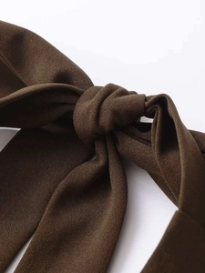 Detail aus dunkelbraunem Kreppstoff mit strukturiertem Knoten und elegantem Fall