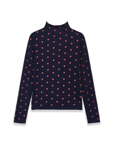 Detailed close-up of dark blue knit top featuring red heart patterns and high neckline