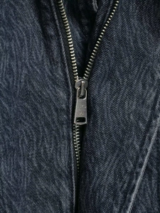 Detail of metallic zipper on vintage gray denim jacket with washed texture finish