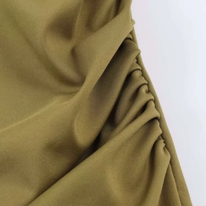 Close-up detail of olive green ruched fabric texture on a slim asymmetric dress