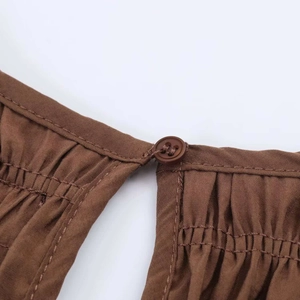 Detailed macro view of dark brown cotton fabric with gathering pleats and button closure