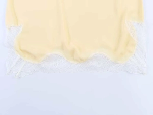 Detailed macro view of yellow camisole fabric with white floral lace scalloped hem