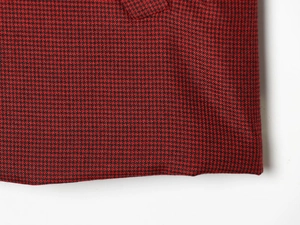 Gros plan sur la texture pied-de-poule rouge et noire et les coutures de l'ourlet