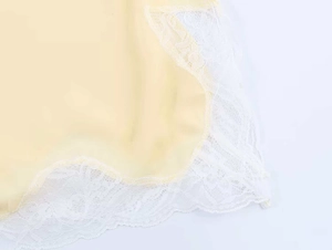 Close-up of pale yellow camisole showing delicate white lace embroidery and fabric texture