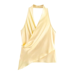 Detail of light yellow satin halter top featuring a cross-wrap design and asymmetric hem