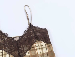 Dettaglio del top sottoveste a quadri vintage con bordo in pizzo floreale marrone e spalline