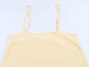 Close-up of pale yellow camisole with delicate white lace trim and adjustable thin straps