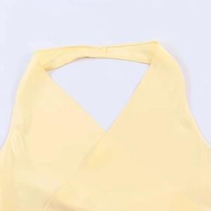 Detailed close-up of light yellow satin halter top with deep V-neckline and smooth texture