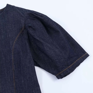 Detail of puff sleeve on dark blue denim dress with orange contrast stitching