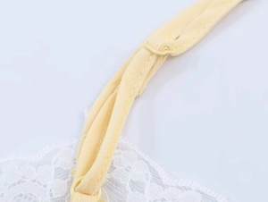 Close-up of adjustable strap and delicate lace detail on pale yellow camisole top