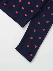 Detailed close-up of navy knit fabric featuring a woven red heart pattern texture
