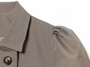 Gros plan d'une veste à carreaux avec col à revers, épaule plissée et bouton en résine