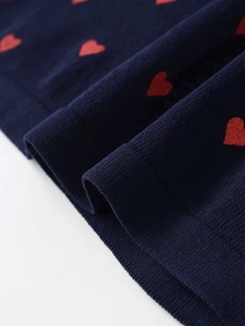 Detailed close-up of navy blue knit fabric with red heart jacquard pattern and fine stitching